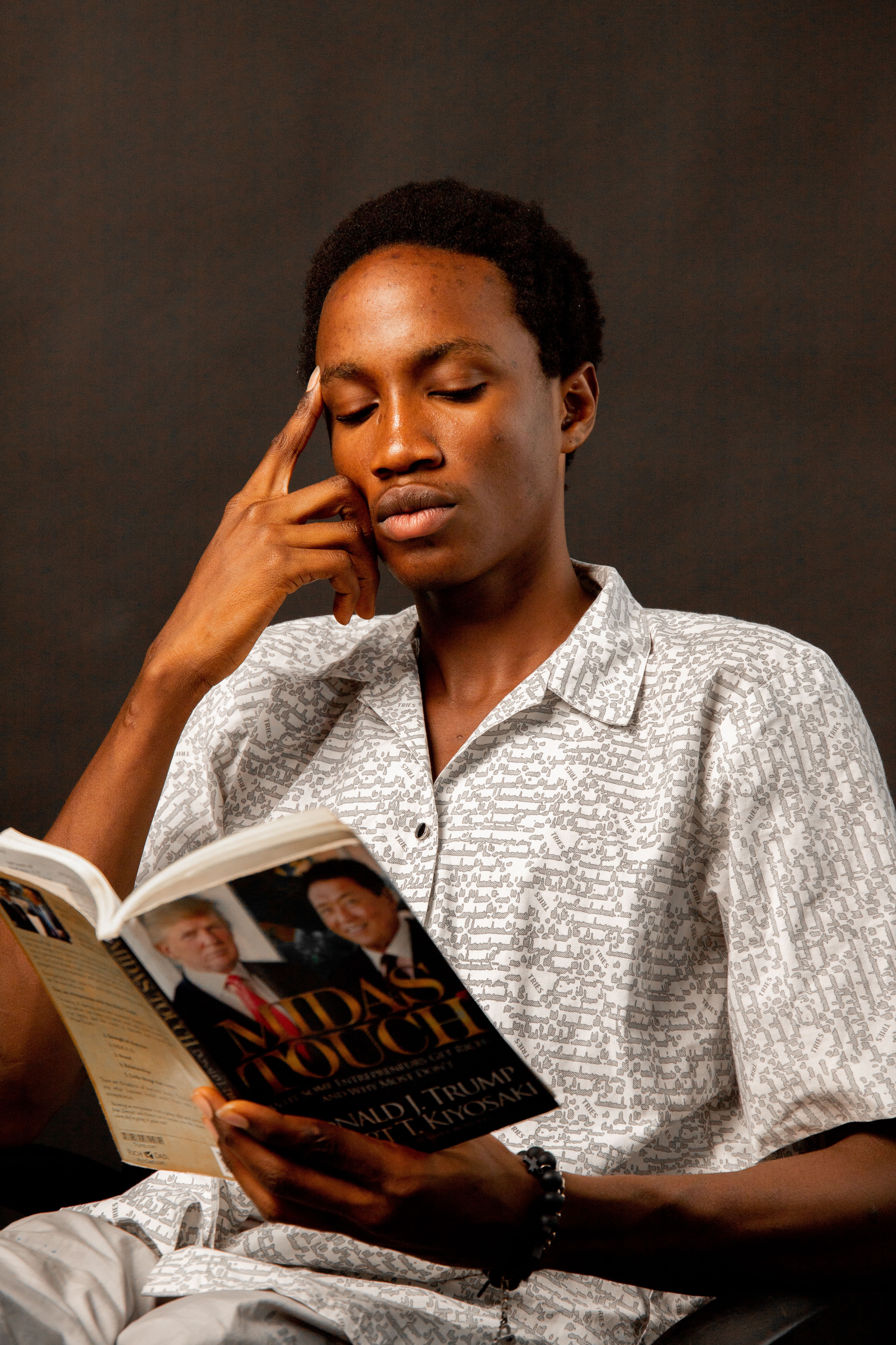 A young man in deep concentration while reading a book indoors.
