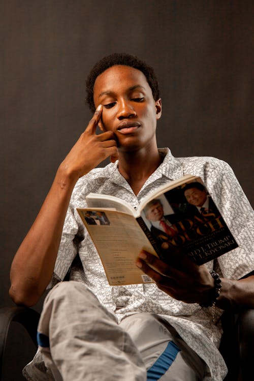 Young Man Sitting and Reading a Book 