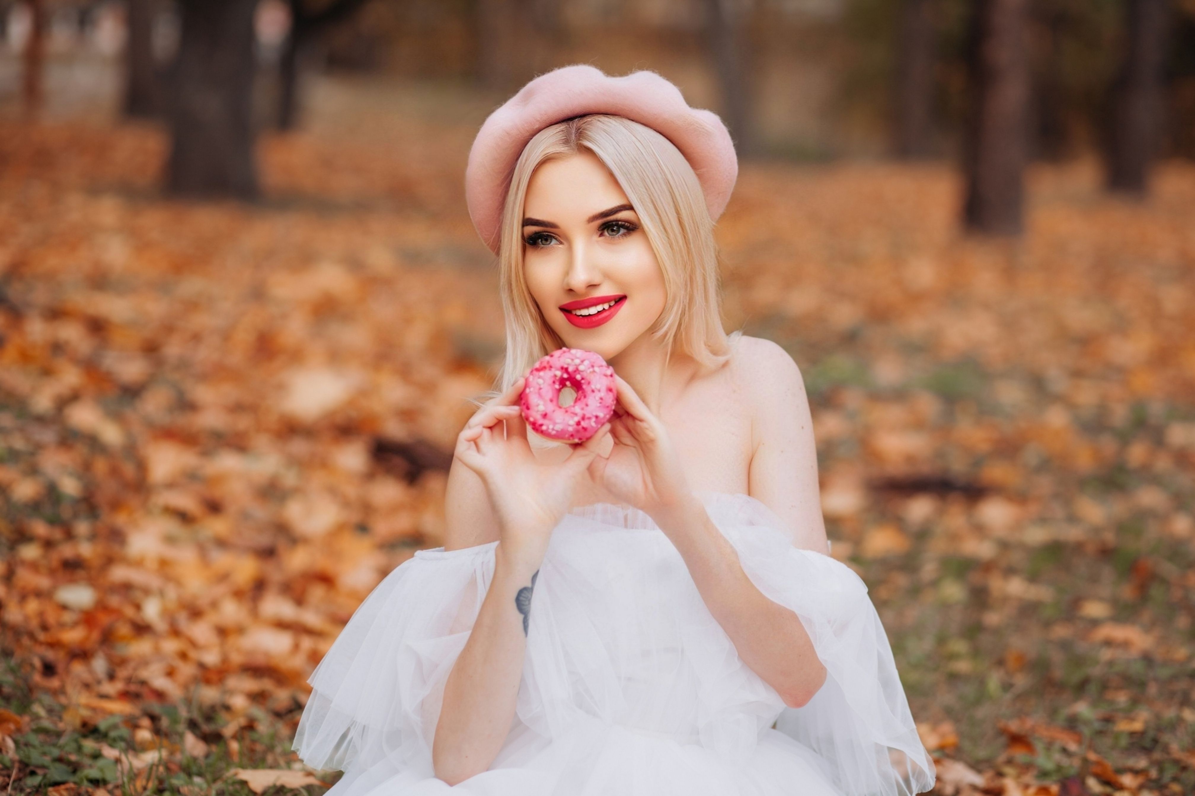 A beautiful blonde woman in a pink hat holding a flower · Free Stock Photo