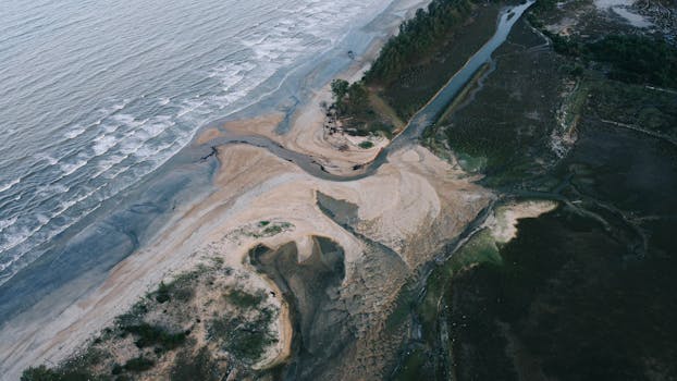 Scenic aerial view of Kuantan's rugged coastline in Malaysia with sandy shores and swirling waves.