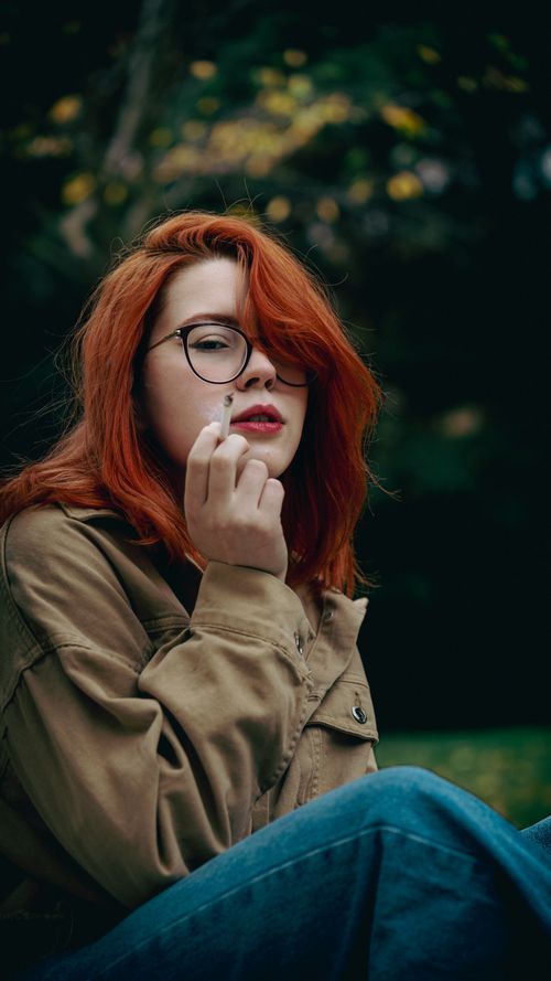 Free Chic portrait of a redhead woman with glasses, smoking outdoors in Ankara. Stock Photo