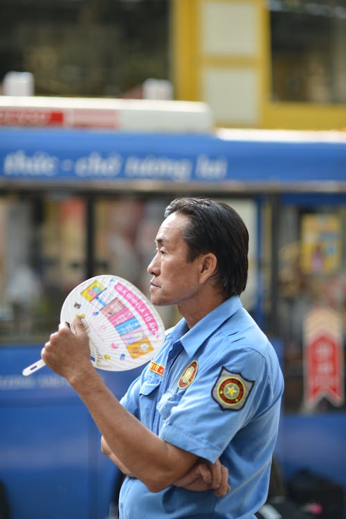 Police Office Standing in the Street and Using a Fan 