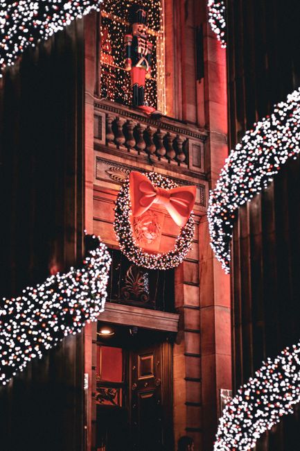 A beautifully decorated building with Christmas lights, wreath, and toy soldier on display.