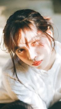 Captivating portrait of a young woman with pale skin and soft sunlight creating a dreamy atmosphere.