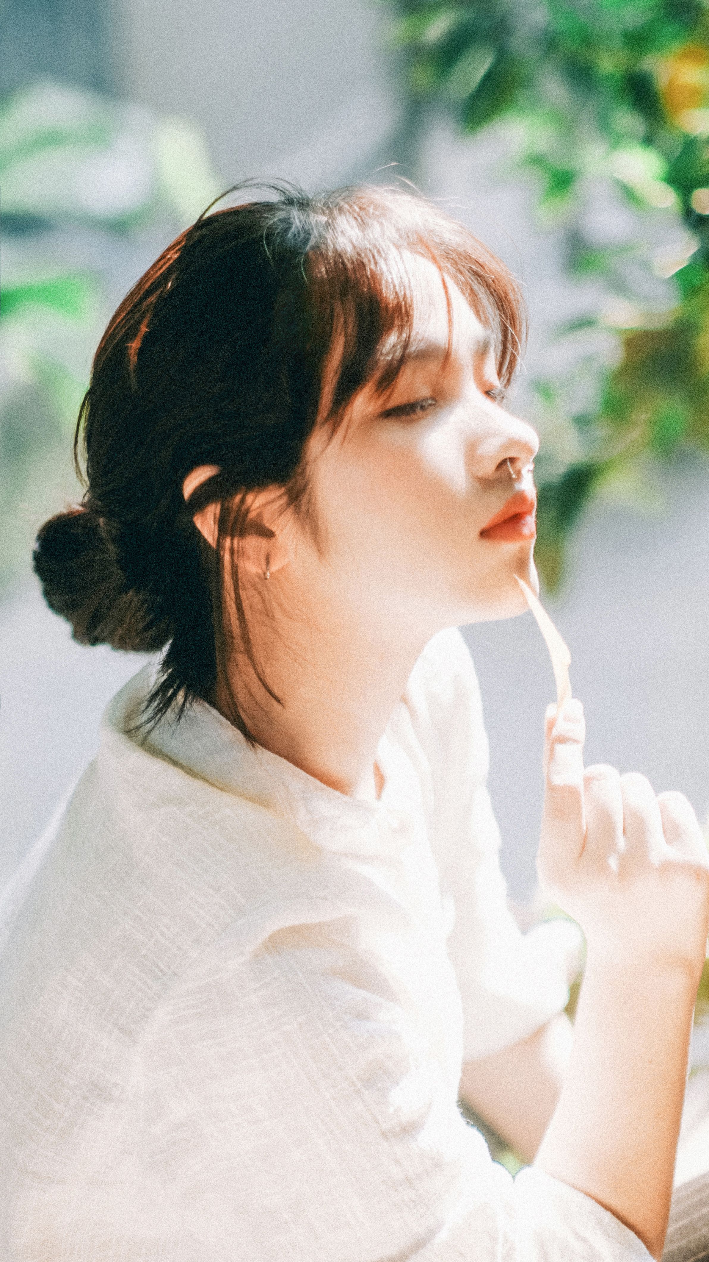 A serene portrait of a woman enjoying sunlight in a lush green garden, exuding tranquility.