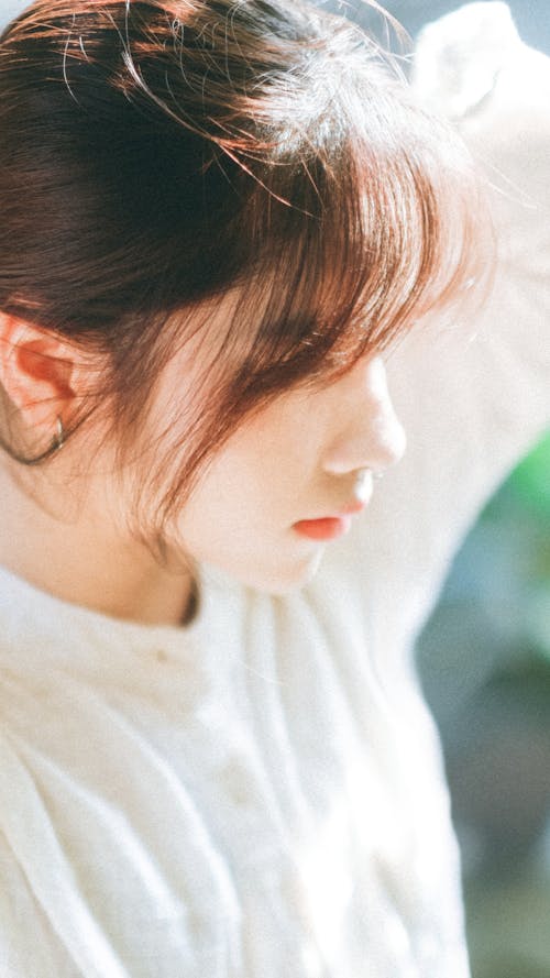 Side View of a Young Woman in a White Blouse Standing in the Sunlight