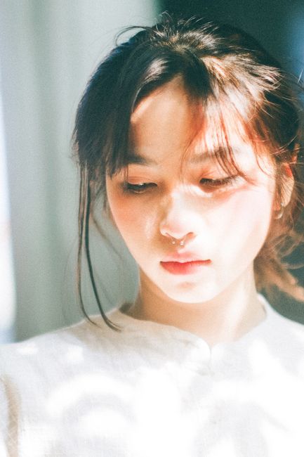 Serene portrait of a young woman in soft sunlight with natural shadows.
