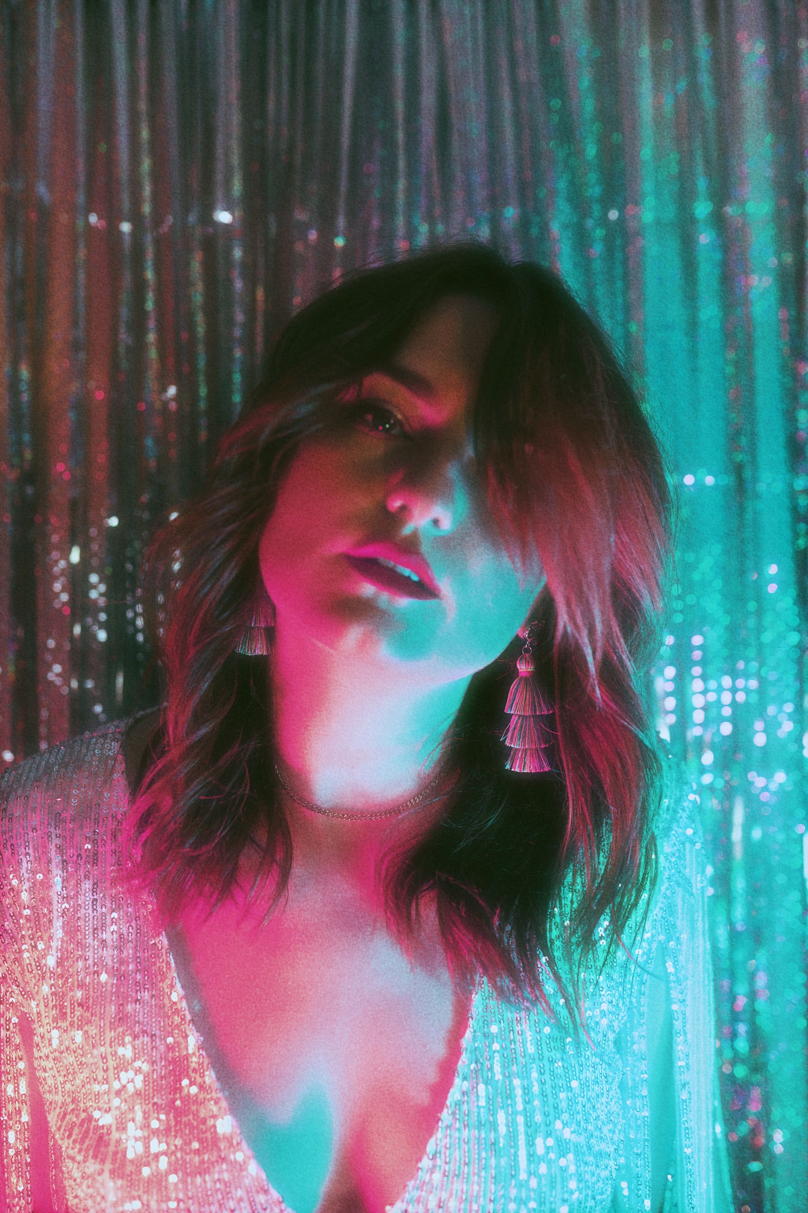 Stylish woman in sparkly dress with dramatic lighting and earrings.