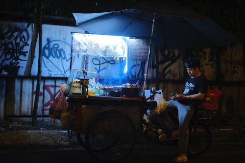 Free A street food vendor at night in an urban alley with neon lights and graffiti. Stock Photo