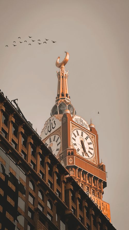 Free The iconic Abraj Al Bait Clock Tower in Mecca stands tall with birds flying over at dusk. Stock Photo