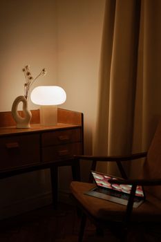 A cozy minimalist workspace with a lamp, laptop, and modern decor in a warm room.