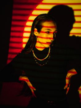 Moody portrait featuring a model with striking striped shadow effects and warm hues.