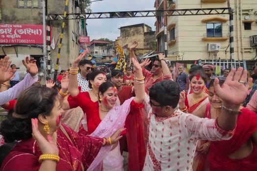People celebrating Durga Puja with dancing and laughter on Kolkata's vibrant streets.