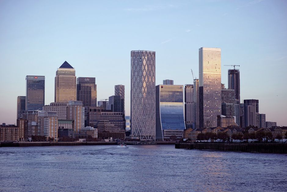 Skyline view of Canary Wharf with skyscrapers reflecting sunset light across the Thames.