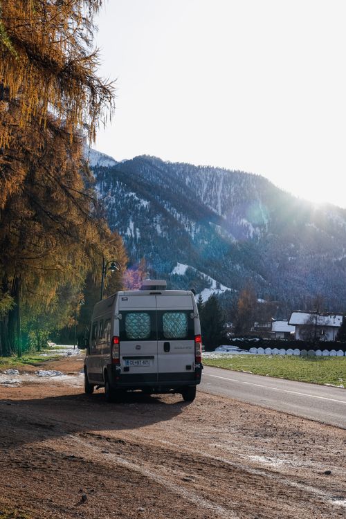 Free A van parked on a rural mountain road with scenic views during sunset, capturing countryside beauty. Stock Photo
