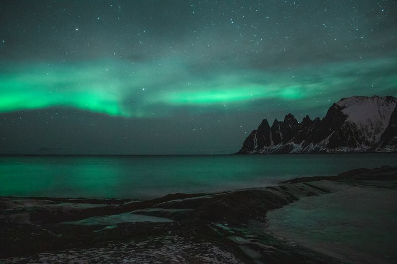 Aurora boreală verde deasupra peisajului arctic