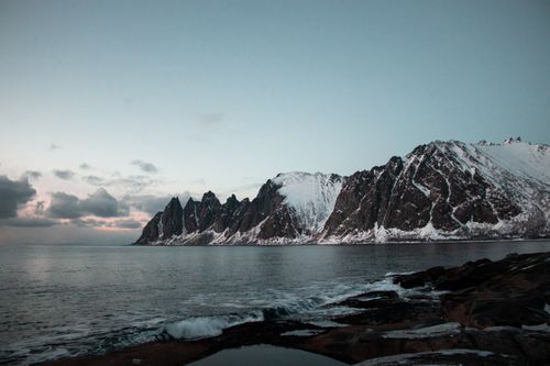 Free Stunning snow-covered peaks reflected in the tranquil ocean at sunset, Norway. Stock Photo