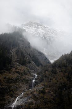 A serene scene capturing a misty mountain with a cascading waterfall in Ginzling, Tirol, Austria.