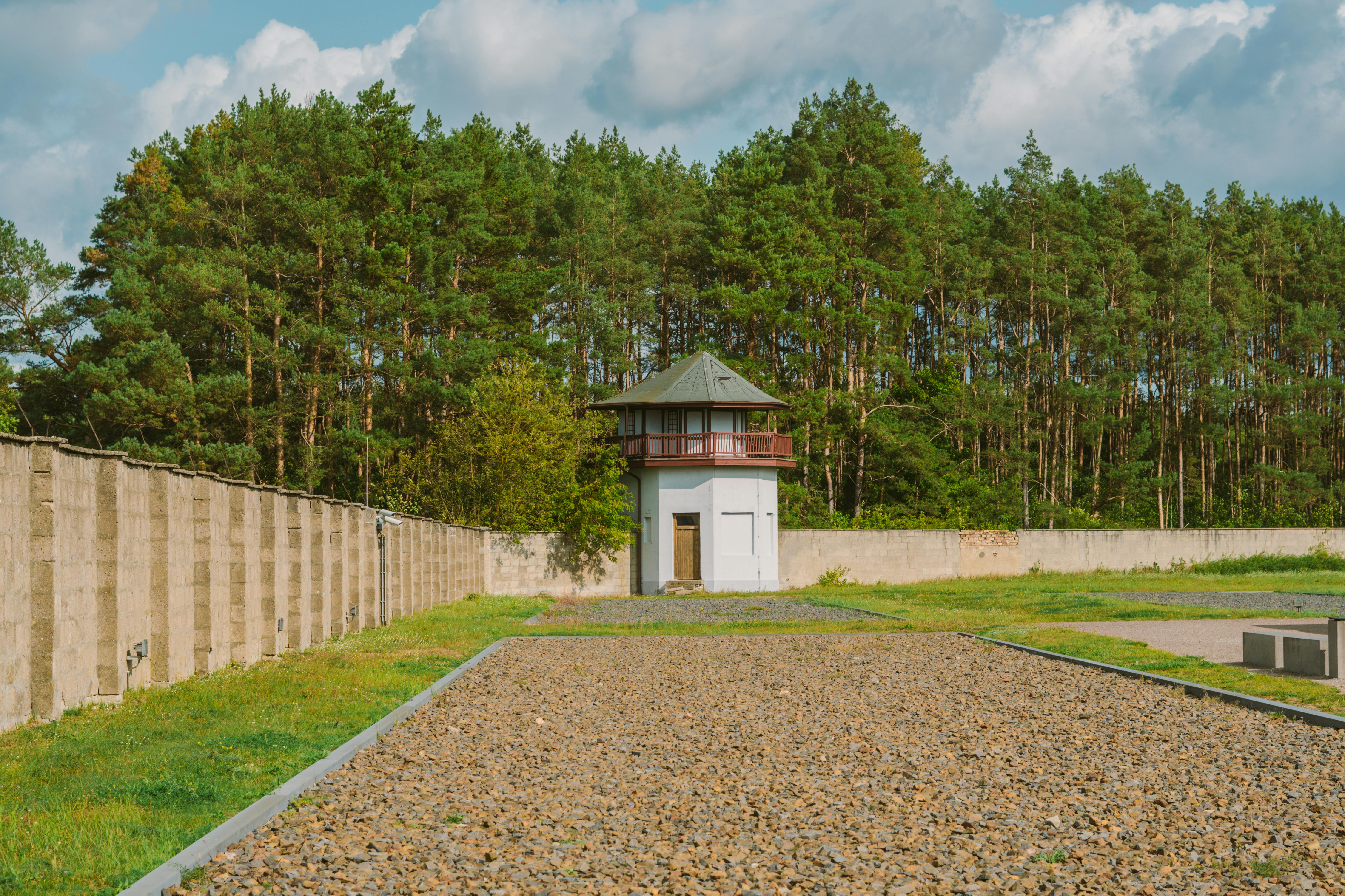 Guard tower surrounded by high walls and trees, showcasing serene landscape in Berlin, Germany.