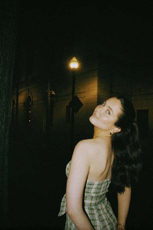 Woman in an Off-the-Shoulder Backless Plaid Dress Posing on the Street at Night