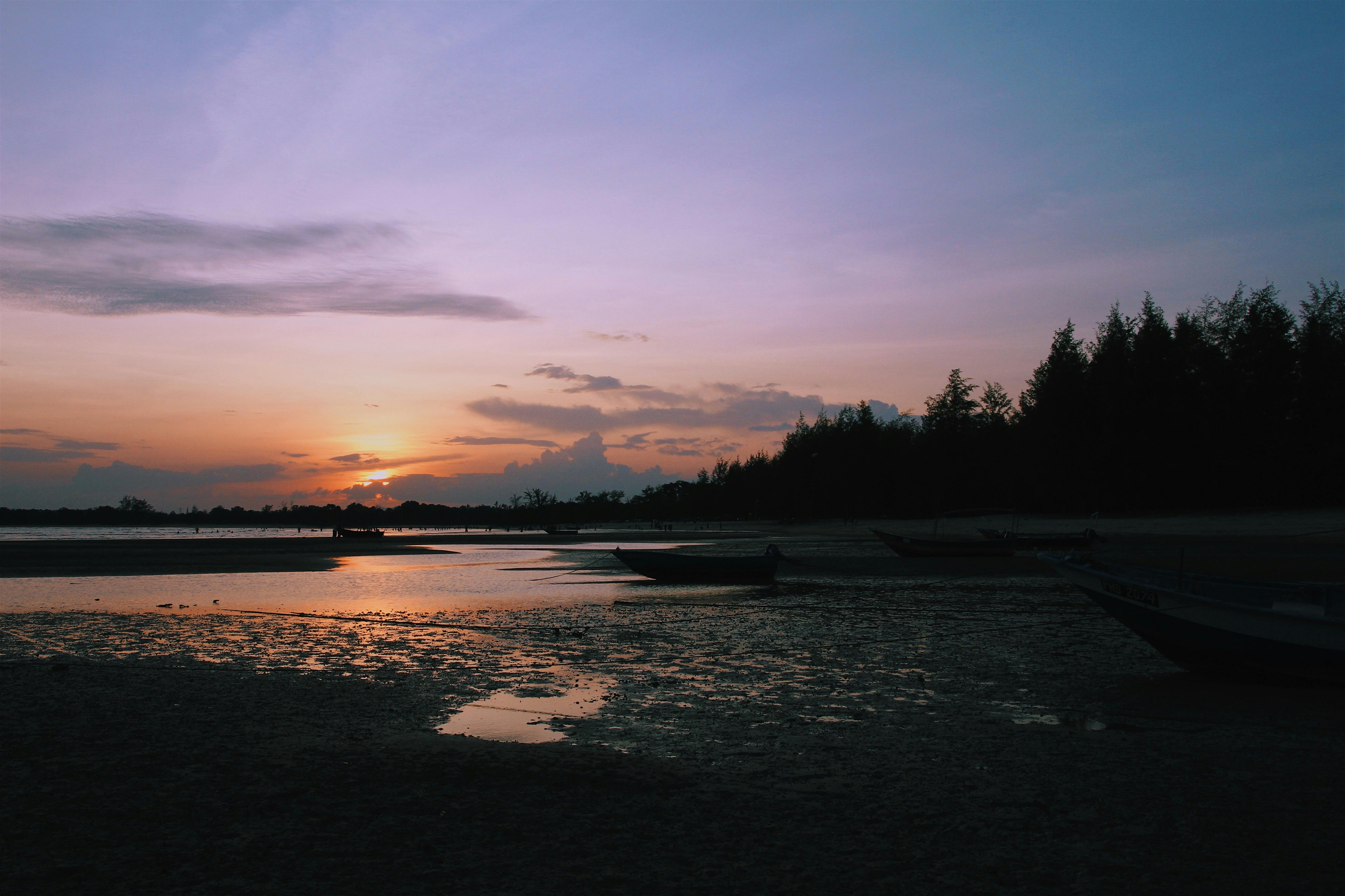 Idyllic sunset view at Balok Beach, Malaysia with boats and tranquil waters.