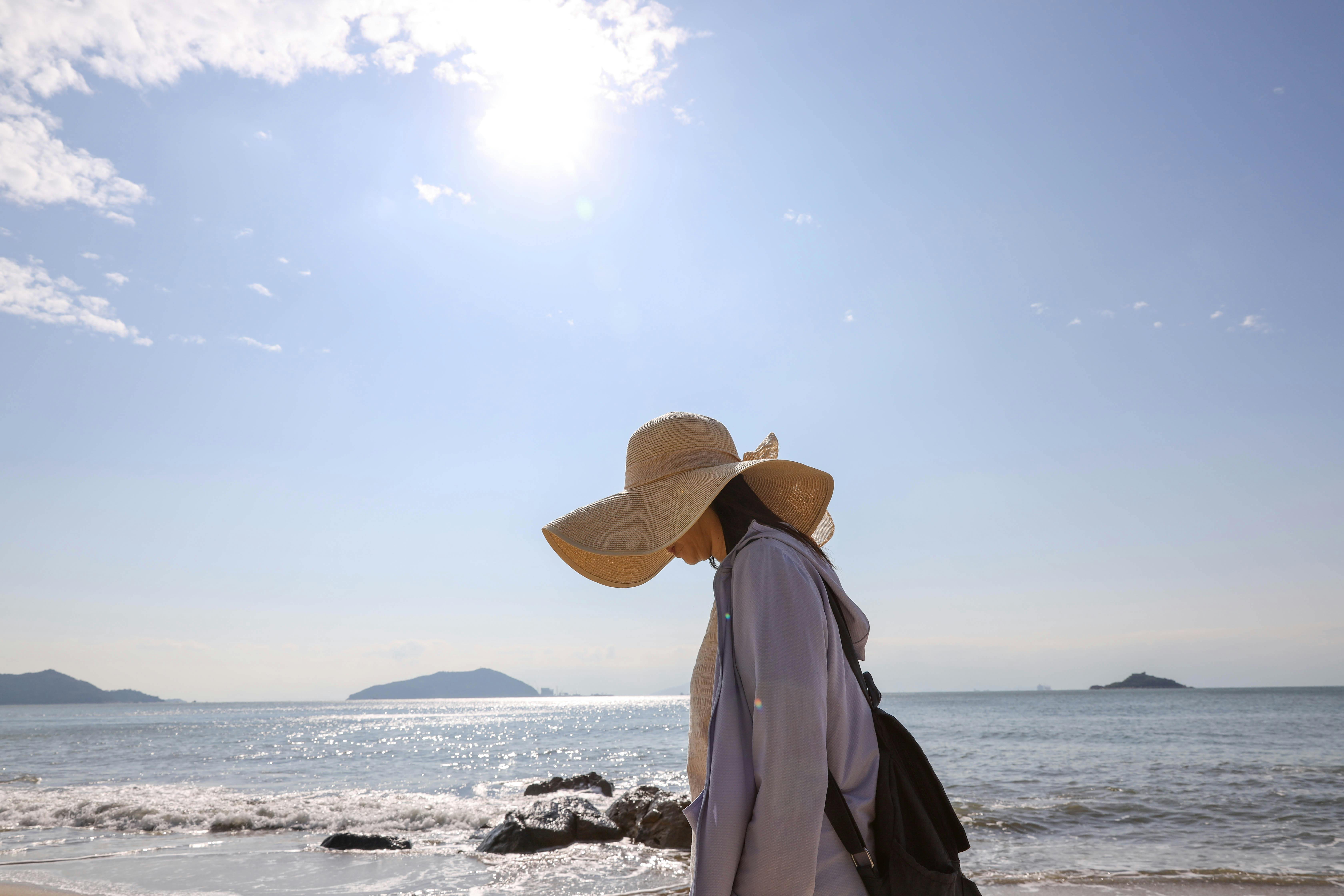 A serene scene of a woman walking on a sunny beach, enjoying a peaceful moment.