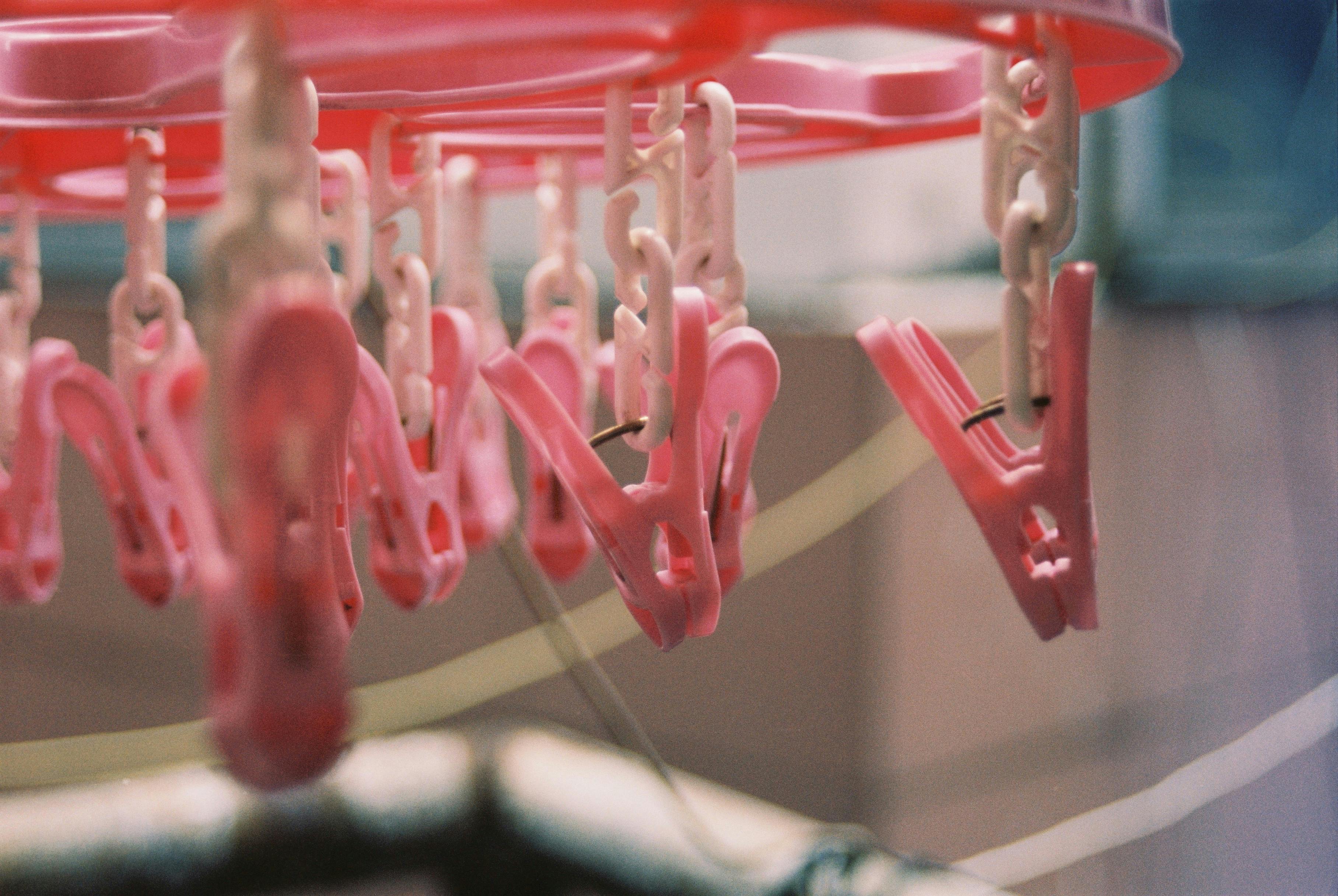 Close-up of pink clothespins on a hanger indoors, captured in soft focus.