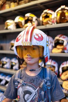A child wearing a Star Wars pilot helmet smiles amidst a store's toy display.