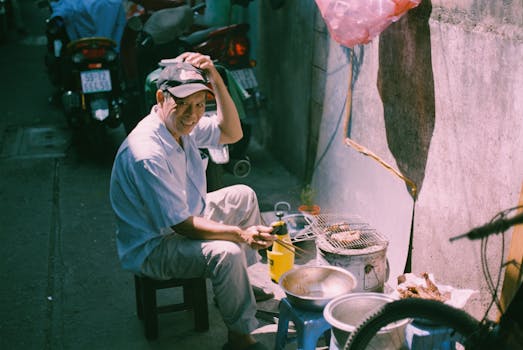 Street vendor grilling food on a sidewalk, showcasing urban life and local cuisine.
