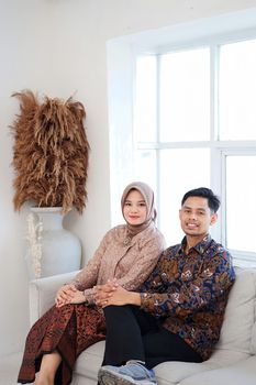 Happy couple sitting on a sofa at home, enjoying a peaceful moment. - Fotografer Sidoarjo