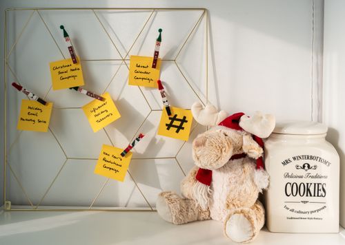 Free A stuffed moose toy beside a note board filled with holiday campaign reminders, creating a festive workspace scene. Stock Photo