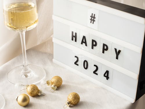 Decorações Festivas Com Taças De Champanhe Sobre Fundo Branco E Uma Mesa De Luz Com A Hashtag #Happy2024