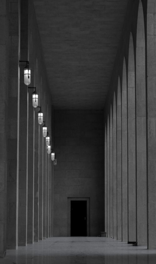 Free Dramatic black and white view of a colonnade with lamps in Bahrain's urban architecture. Stock Photo