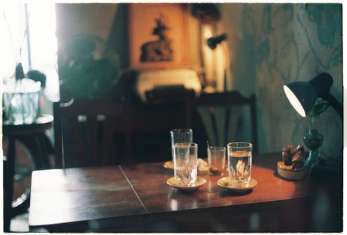 Free A warmly lit indoor scene featuring a table with glasses and a lamp. Stock Photo