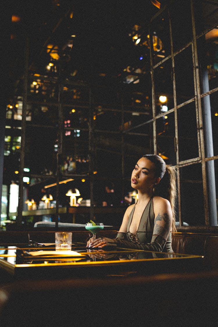 Woman Sitting By Table In Restaurant At Night