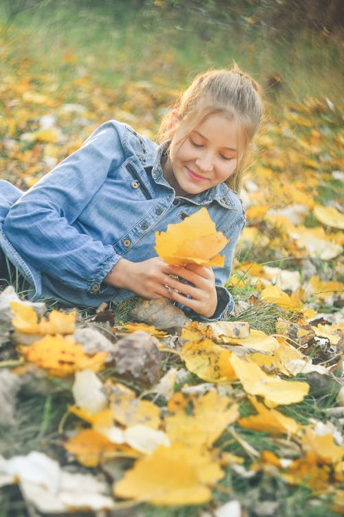 Woman Lying on Ground Covered with Yellow Leaves 