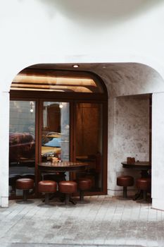 Inviting outdoor cafe seating under a stylish archway with circular tables and chairs.