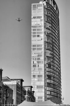 Black and white urban scene featuring a towering skyscraper and drone in flight.