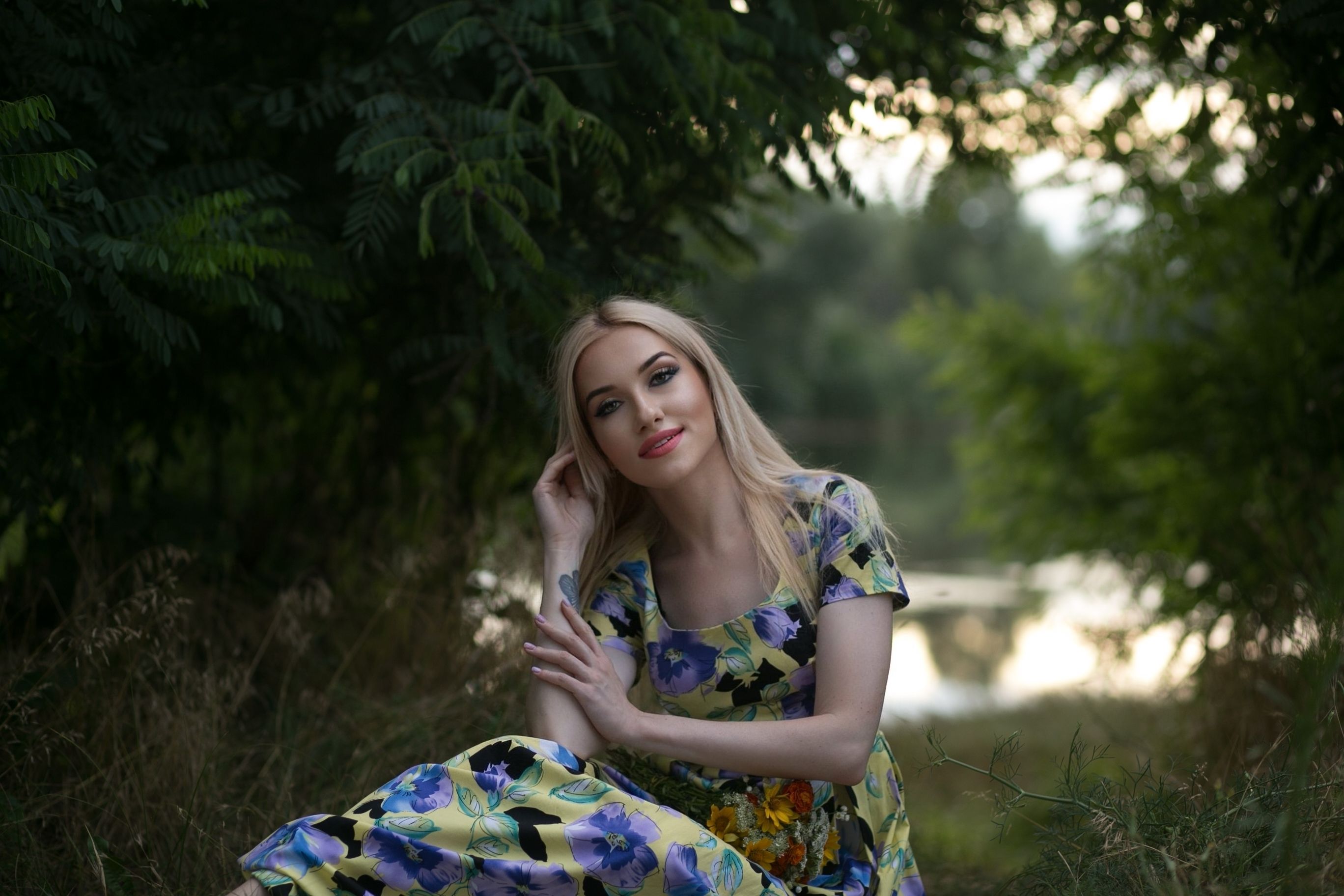 A woman in a floral dress sitting on the grass · Free Stock Photo