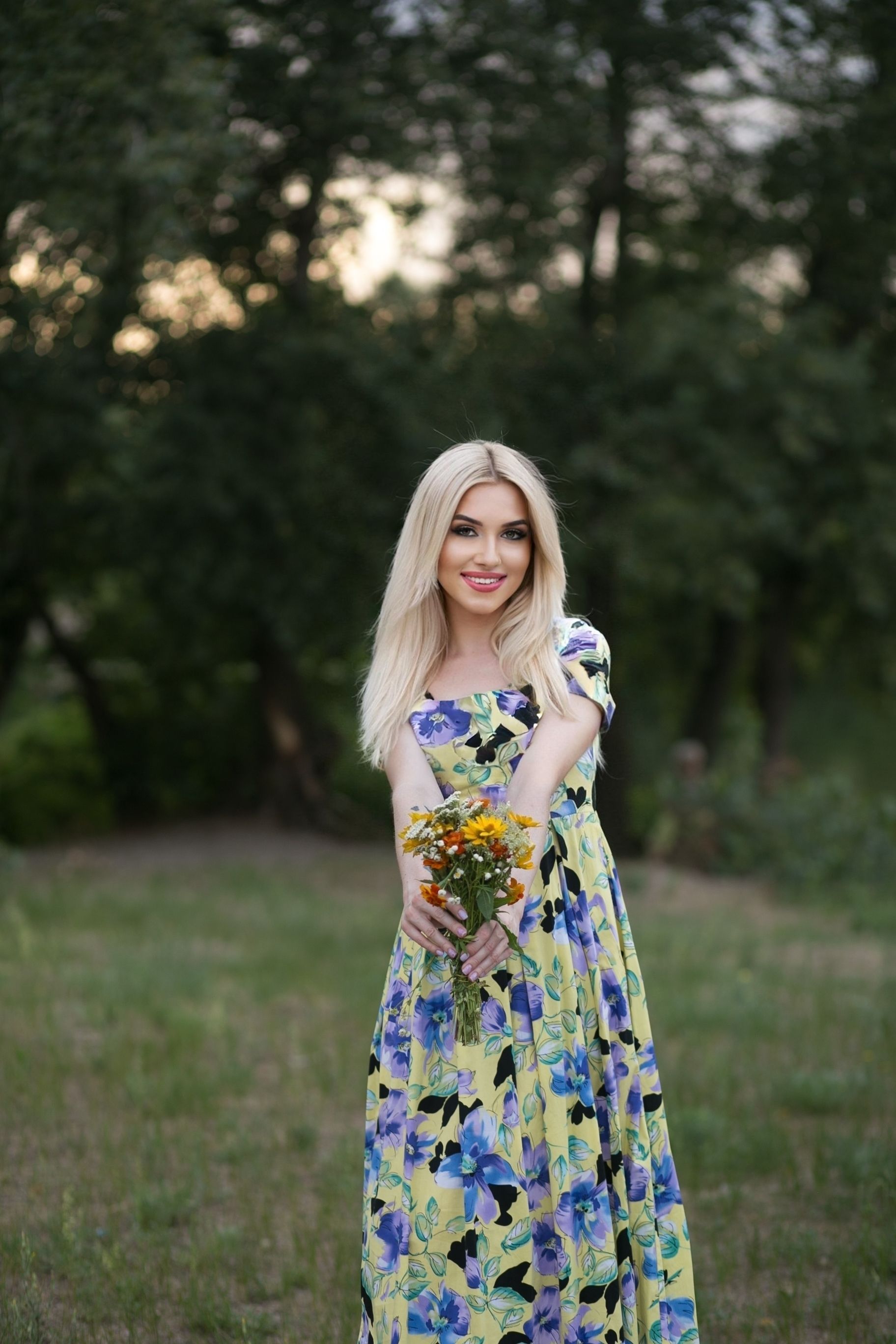 A woman in a long floral dress holding a bouquet · Free Stock Photo