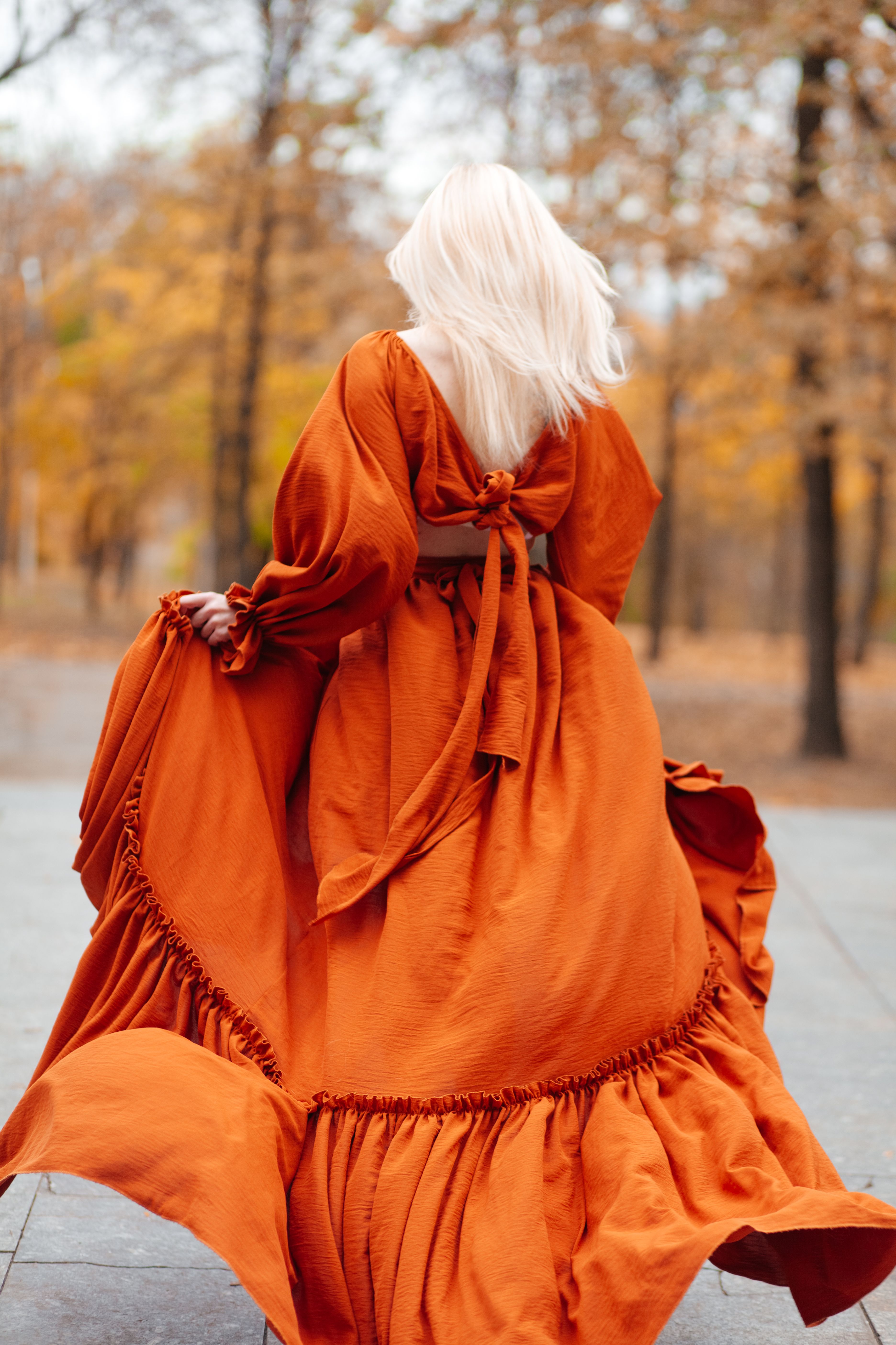 A woman in an orange dress walking through a park · Free Stock Photo