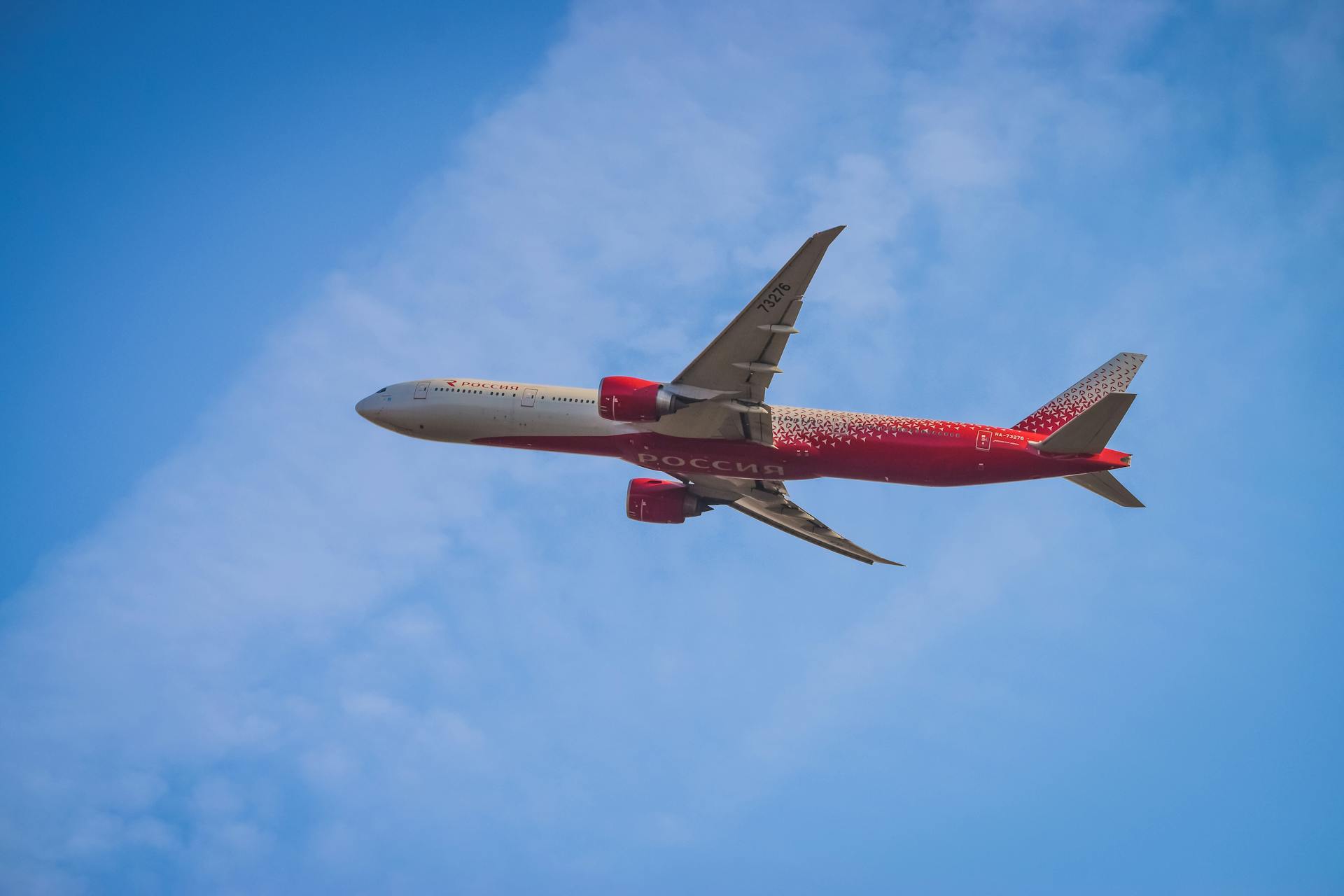 A red passenger airplane soaring through a clear blue sky, showcasing modern air travel.