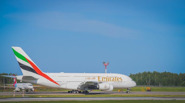 Emirates aircraft taxiing on the runway at an airport on a clear sunny day.