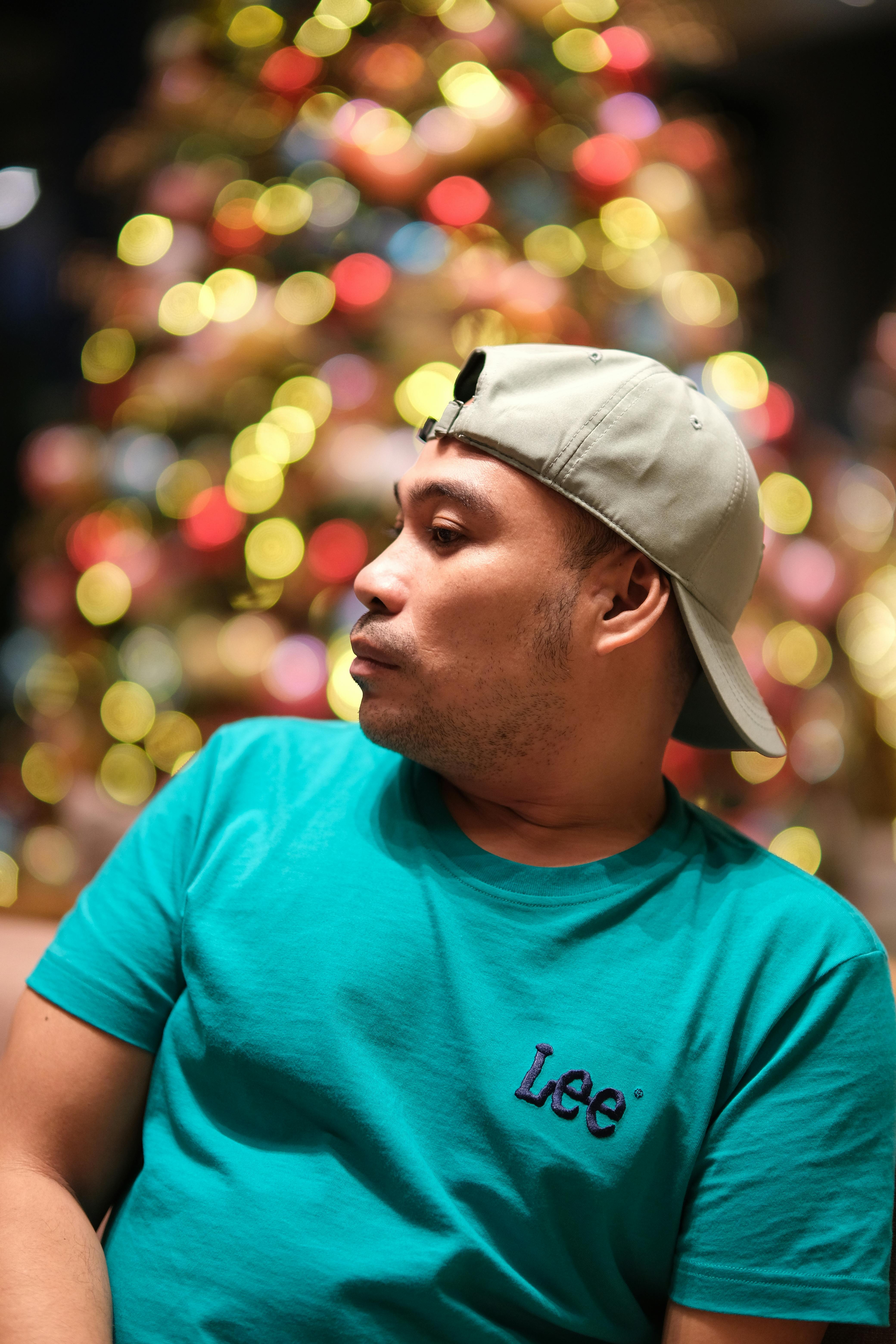 Profile shot of a man wearing a baseball cap with festive bokeh lights in the background.