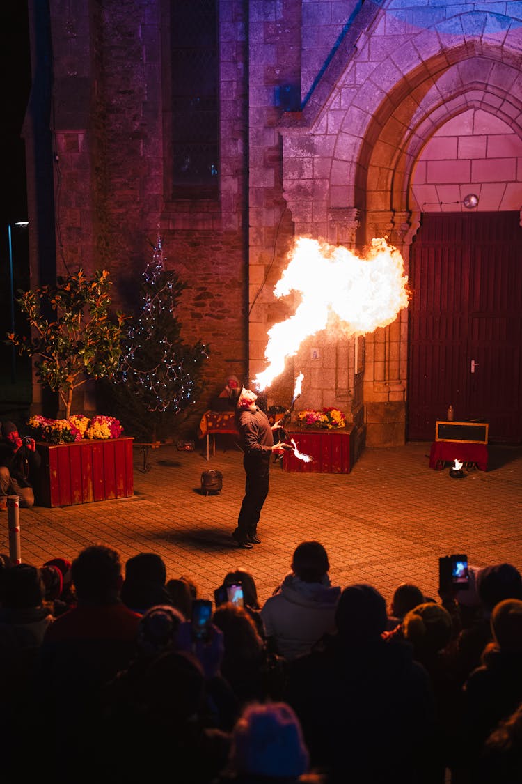 Performer Fire Spitting In Front Of Audience At Night