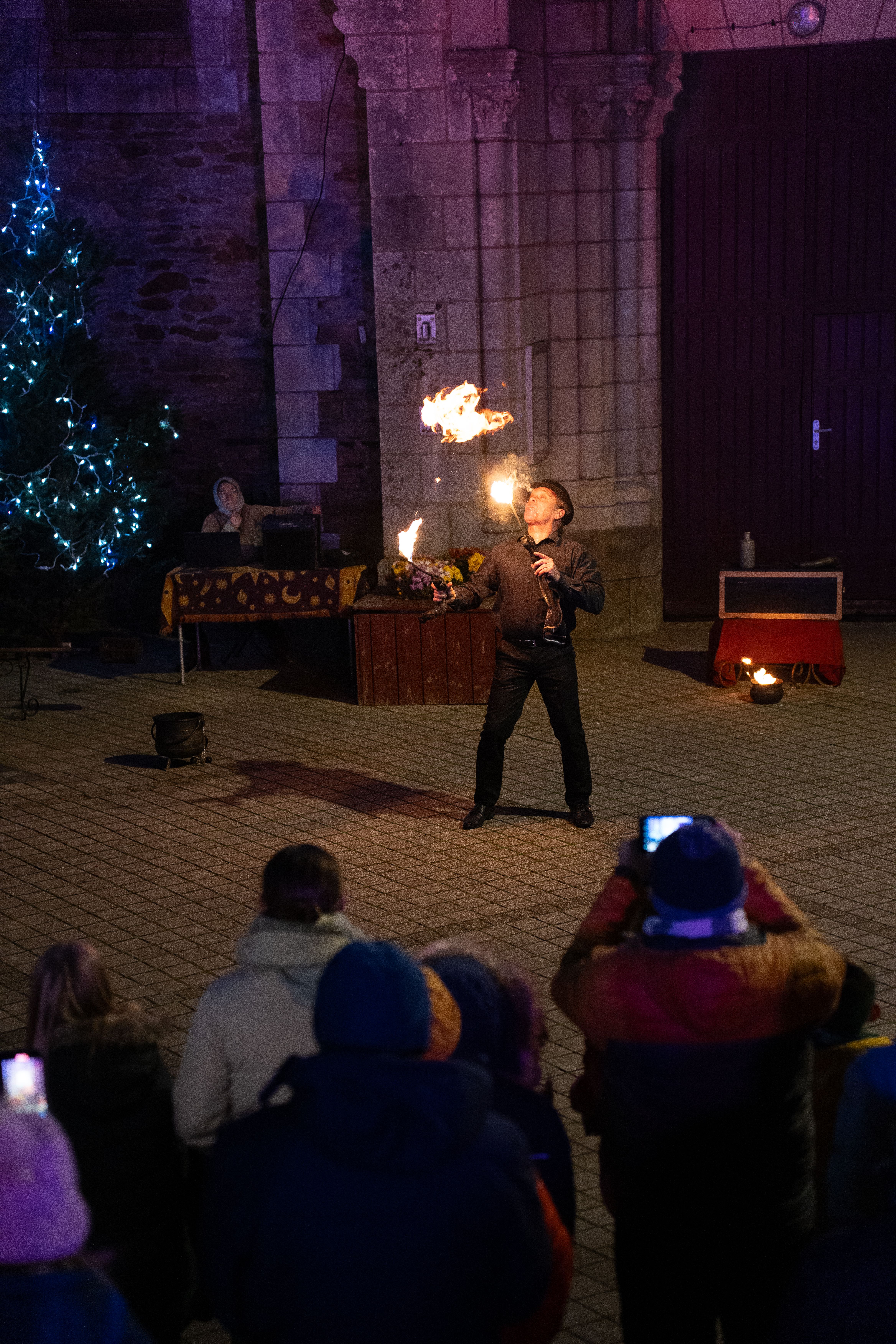 A captivating fire juggling performance in a city square during a festive night event.