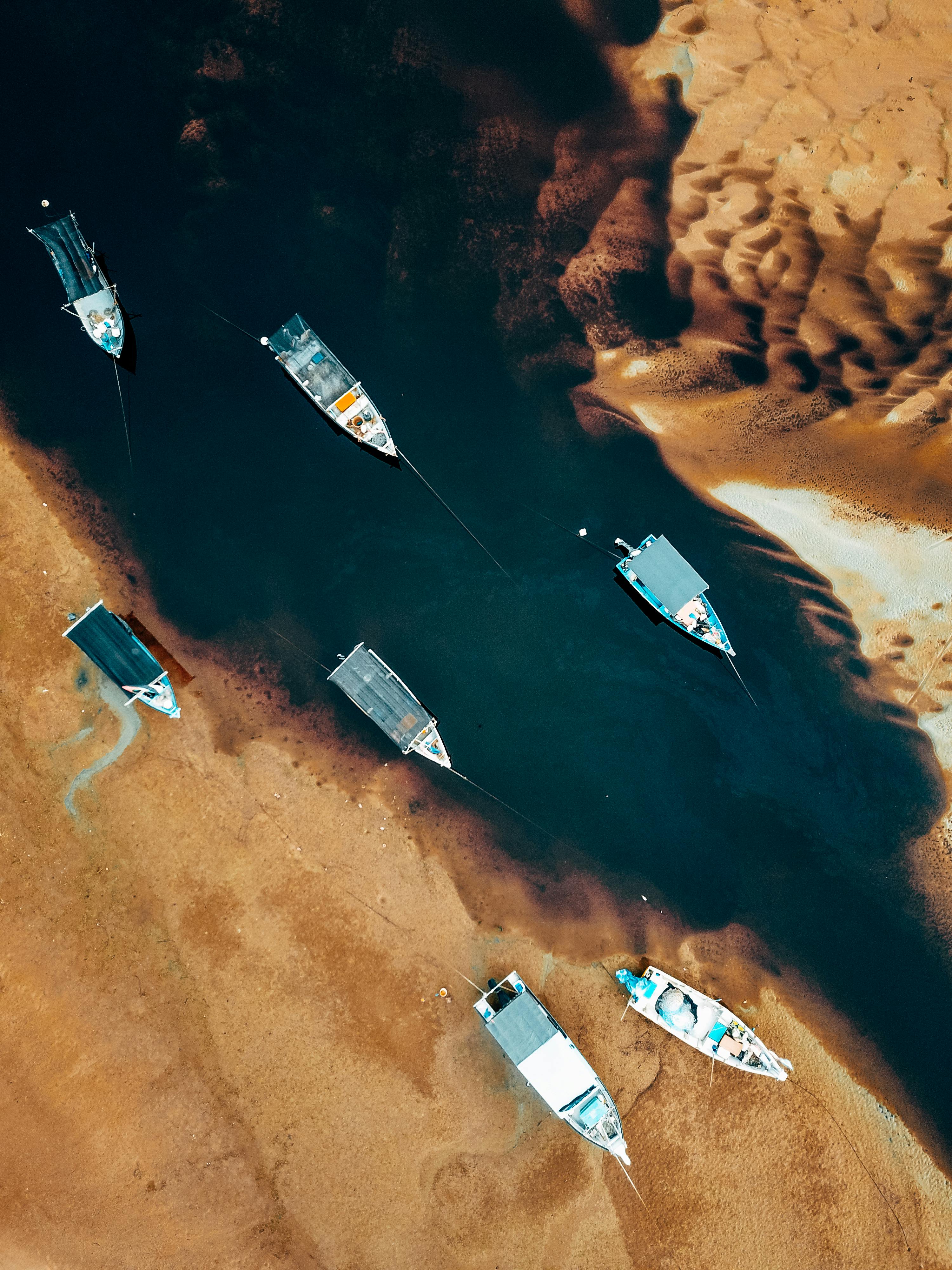 Aerial image of fishing boats anchored on a river with sandy banks in Chukai, Malaysia.