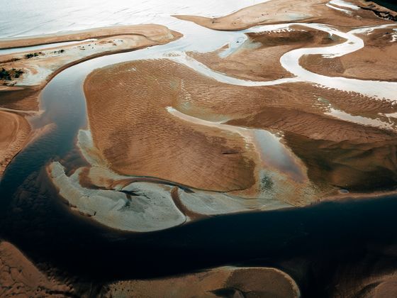 Aerial view of a tidal channel cutting through an estuary, photo by Pok Rie on Pexels