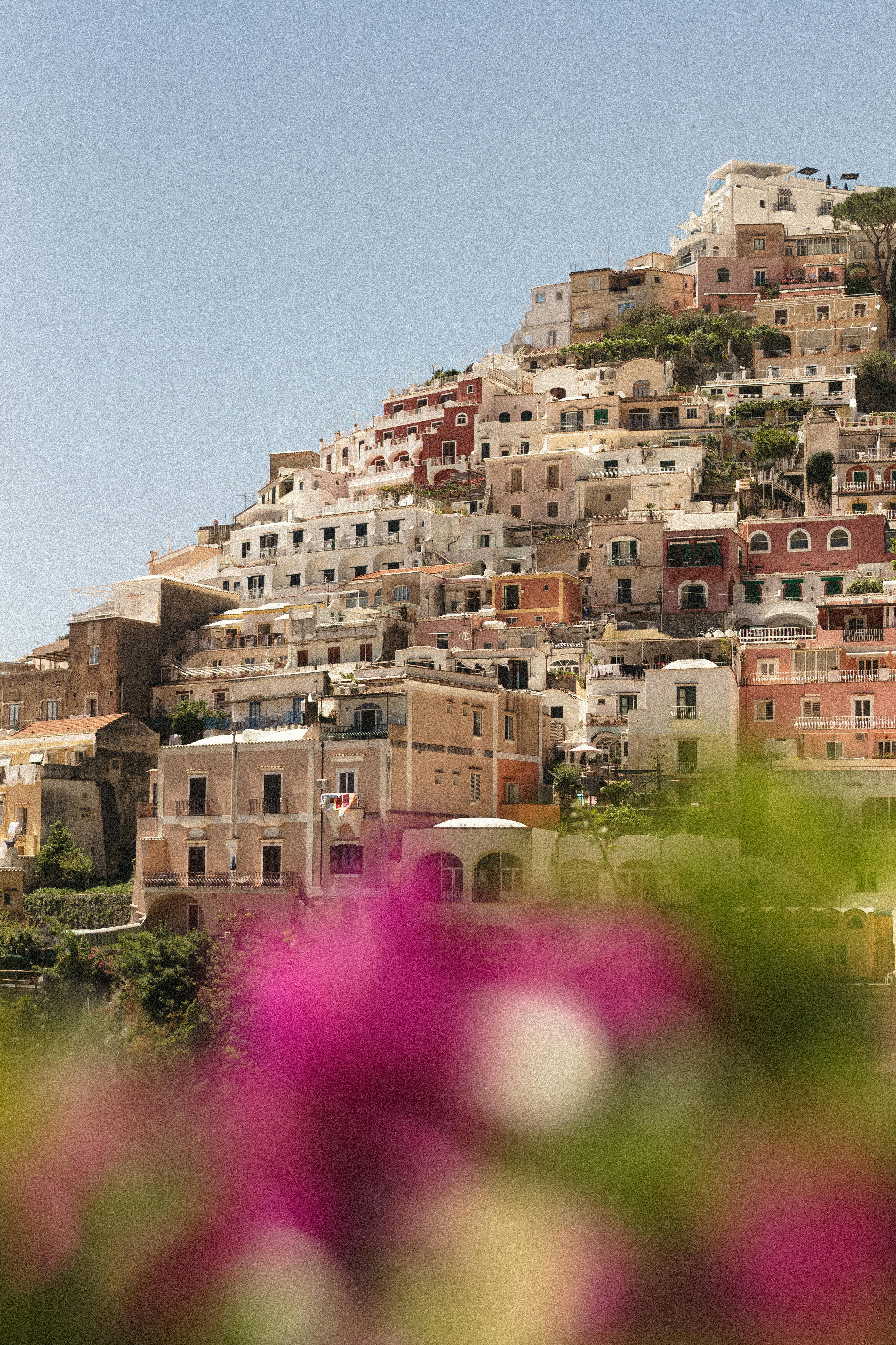 Charming Amalfi Coast town view with vibrant houses and blurred flowers.