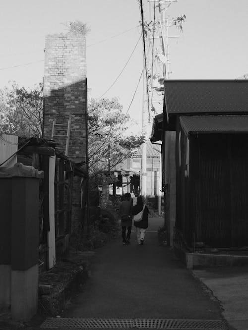 People Walking in Narrow Alley in Town in Black and White